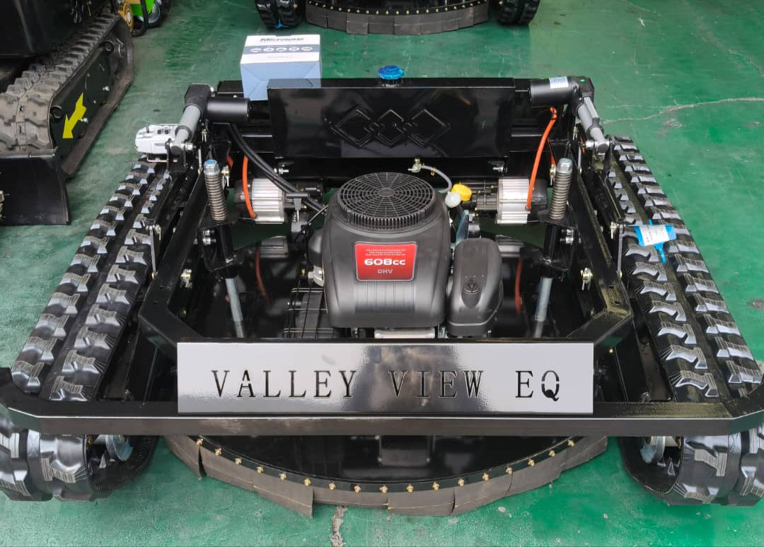 Robotic vehicle with tracks and visible branding on a green floor