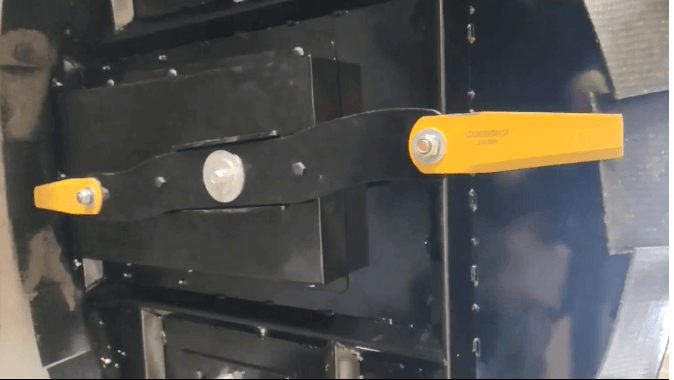 Close-up of the mechanism of a remote grass cutter showing metal components and yellow handles.
