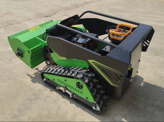 Green and black tracked machine on a concrete surface with vehicles in the background
