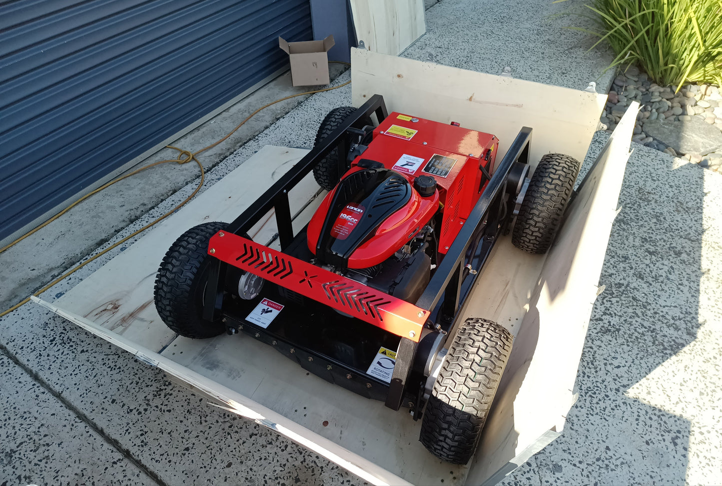 Red lawn mower on a white platform outside a building