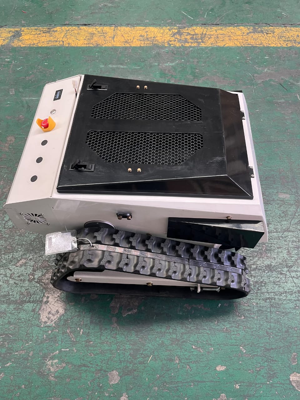 Robotic device with a black top and gray bottom on a green floor.