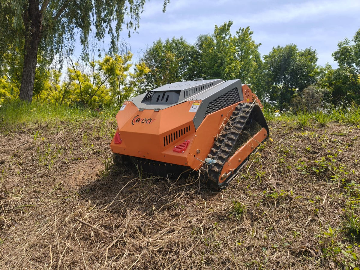 Redback remote control lawn mower navigating rough terrain with its steel body and tracked design.