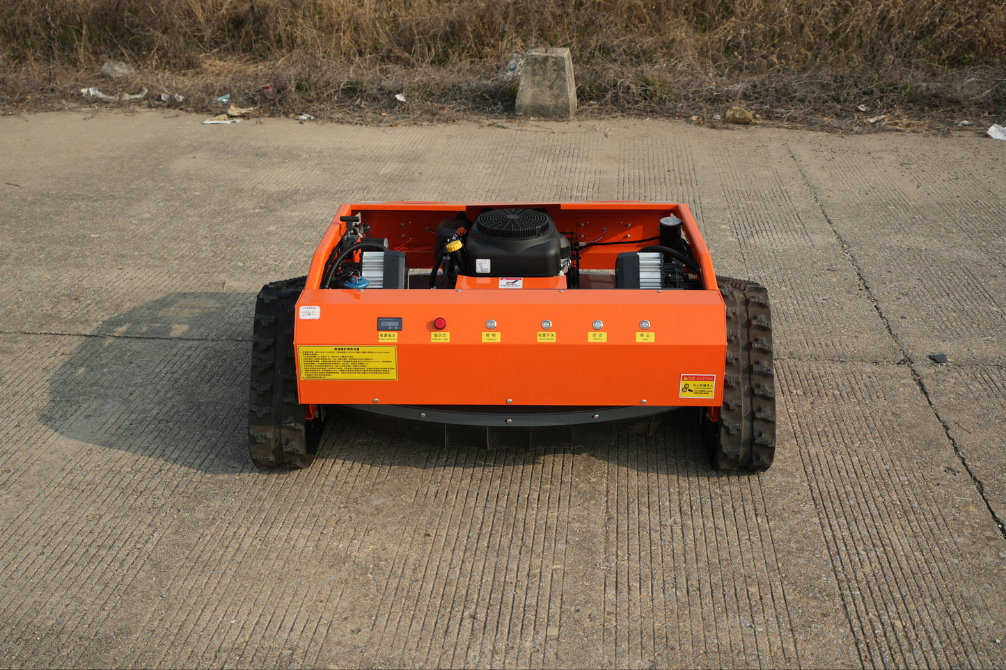 RC lawn mower on a concrete surface with a grassy area in the background
