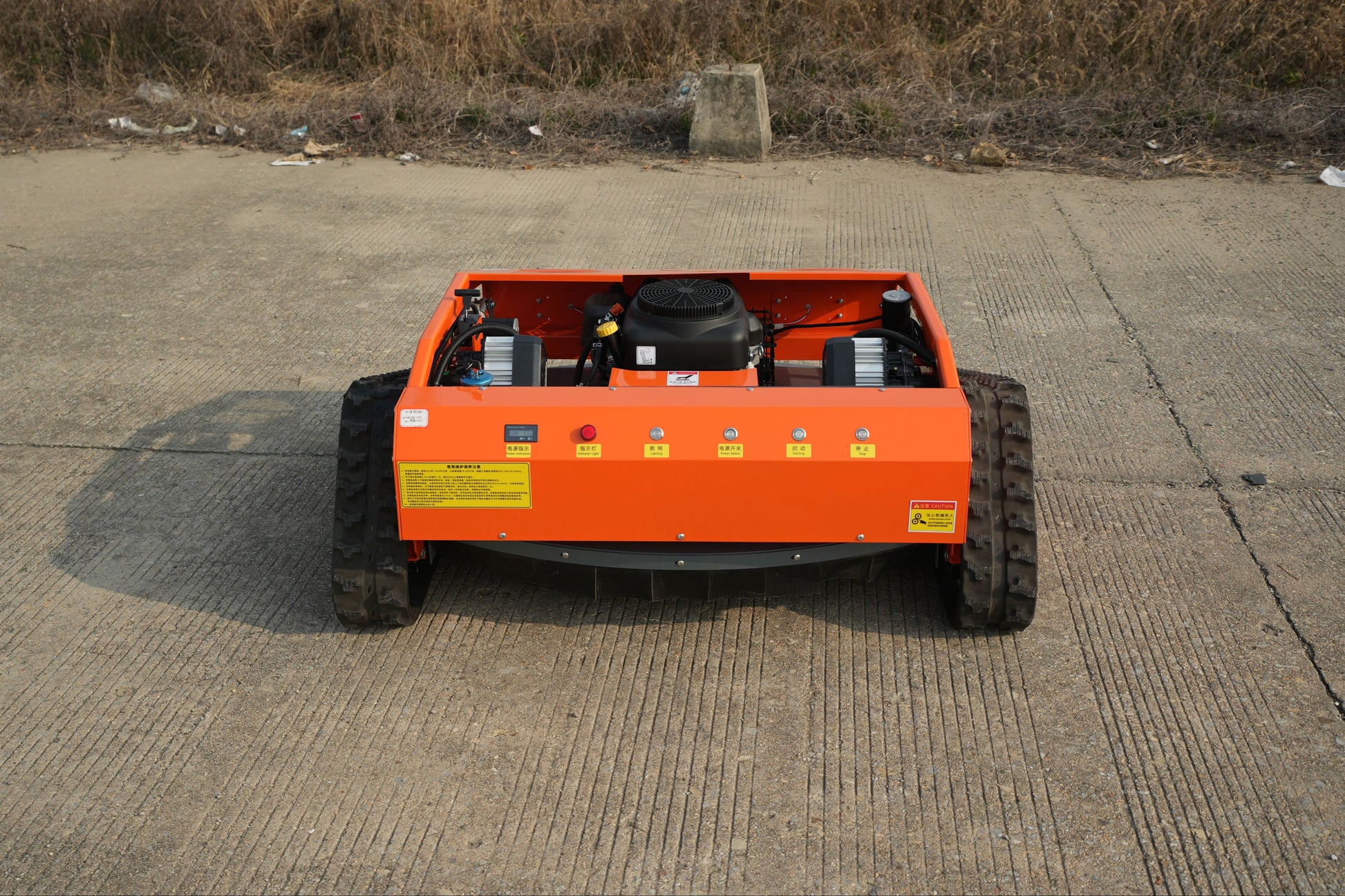 RC lawn mower on a concrete surface with a grassy area in the background