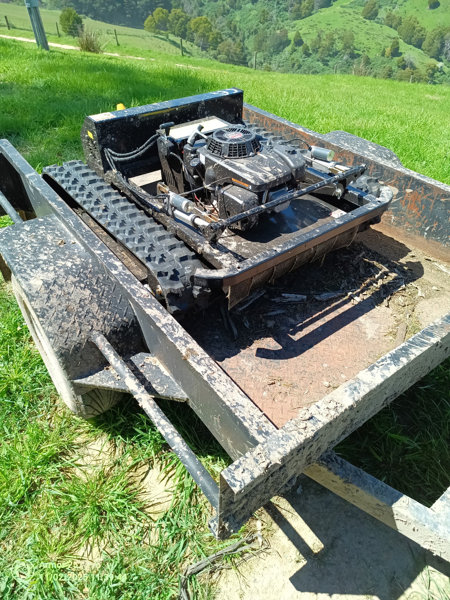 Remote control lawn mower Victoria Tank 600mm on a trailer in a grassy field, designed for challenging terrain.