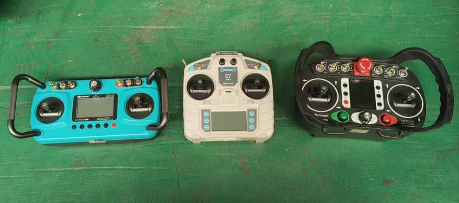 Three remote control devices on a green surface